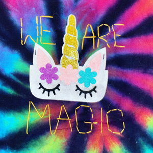 "We are magic" stitched onto tie dye fabric with a unicorn head in the middle